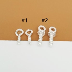 Puede incluir: Dos juegos de baúles de pendientes de tornillo de plata. El primer juego tiene dos baúles con un bucle en la parte superior. El segundo juego tiene dos baúles con una parte superior redonda.