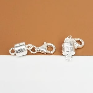 May include: Two silver magnetic clasps for necklaces or bracelets. Each clasp has a round magnetic piece with the inscription "925" and a lobster claw clasp.