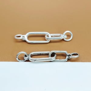 May include: Two silver chain links, each with a rectangular shape, are connected together. The links are smooth and shiny.