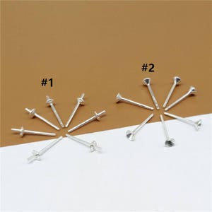 May include: Two sets of silver earring findings. The first set, labeled #1, has a flat, round top. The second set, labeled #2, has a cone-shaped top.