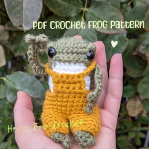 Puede incluir: Una rana de crochet con un mono. La rana es verde con ojos negros y una boca blanca. El mono es amarillo. La rana está sentada en una mano. El texto "PDF CROCHET FROG PATTERN" está en la parte superior de la imagen.