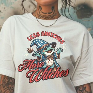 May include: White t-shirt with a cartoon frog wearing a wizard hat and the text "Less Snitchers More Witches".