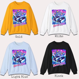 May include: A selection of crewneck sweatshirts in gold, white, light blue, and black. Each sweatshirt features a colorful graphic of orcas, a cruise ship, and the text "Bat the Beat".