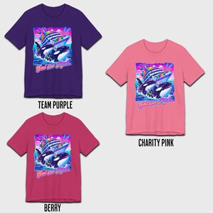 May include: Three t-shirts with a graphic print of a cruise ship and two orcas. The text on the shirts says "Eat the Rich". The shirts are in the colors purple, pink, and berry.