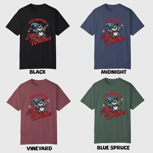 May include: Four t-shirts in different colors with a cartoon illustration of a witch with the text "Less Snitchers More Witches" printed on the front. The colors are black, midnight blue, burgundy, and green.
