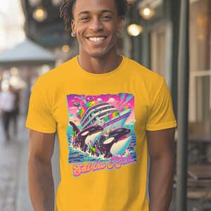May include: A yellow t-shirt with a graphic of two orcas attacking a cruise ship. The graphic is in a retro 90s style with bright colors and a rainbow. The text "Eat the Rich" is below the graphic.
