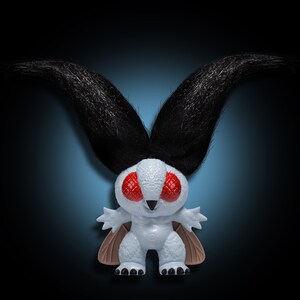 May include: A white plush toy with black fur antennae and red eyes. The toy is shaped like a moth with wings and a small body.