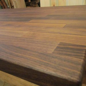 May include: A close-up of a dark brown wooden countertop with a smooth, polished finish. The wood grain is visible and the surface is free of any scratches or blemishes.