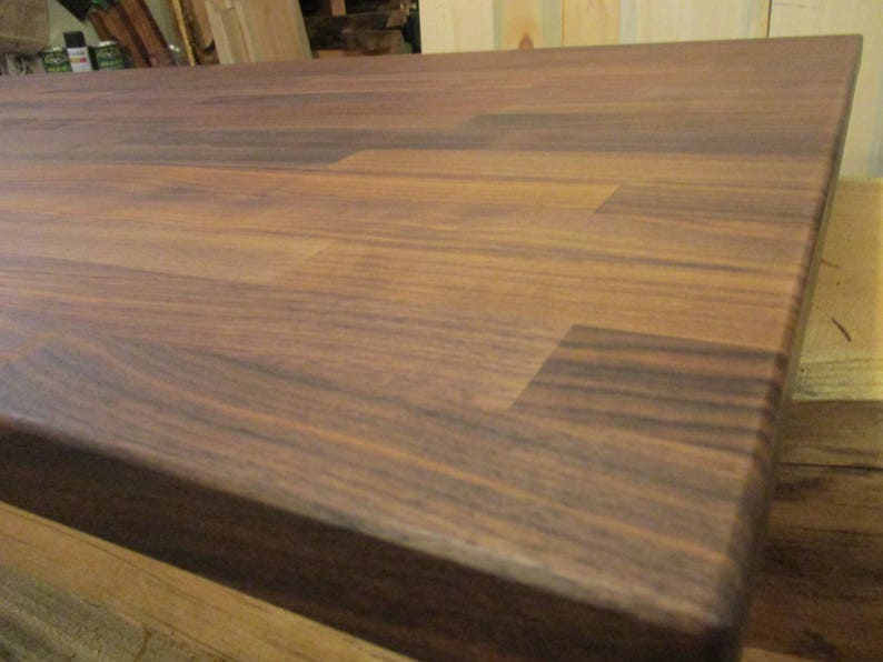 May include: A close-up of a dark brown wooden countertop with a smooth, polished finish. The wood grain is visible and the surface is free of any scratches or blemishes.