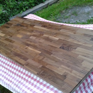 May include: A large, rectangular wooden countertop made of walnut wood planks. The countertop is unfinished and has a natural wood grain.