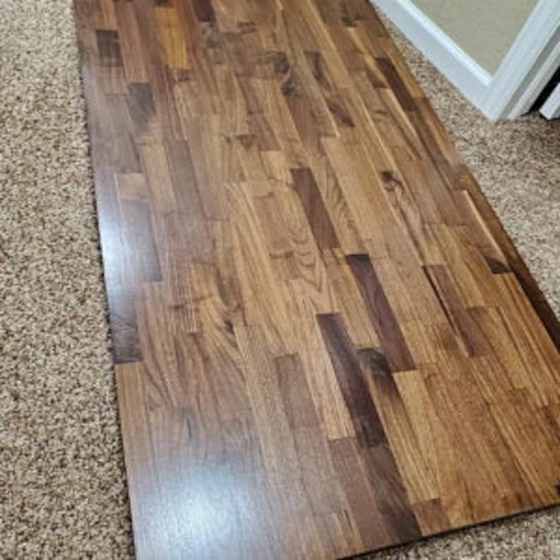 May include: A large, rectangular wooden countertop made of dark brown wood planks. The planks are arranged in a staggered pattern, creating a unique and rustic look.