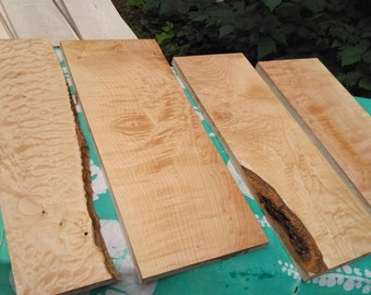 May include: Four pieces of wood with a natural wood grain pattern. The wood is light brown in color and has a smooth surface. The wood is arranged in a row on a green and white tablecloth.