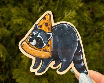 May include: A raccoon wearing a pizza slice hat and holding a pizza slice in its paws. The raccoon is black and gray with a white face. The pizza slice is yellow with red pepperoni and cheese.