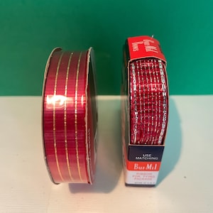 May include: Two spools of ribbon. One is a deep red with gold vertical stripes. The other is a bright red with silver vertical stripes. The packaging for the second spool reads "Bur-Mil Ribbon for Tying Package".