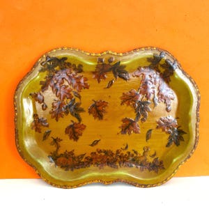 May include: An oval serving tray with a scalloped edge featuring a golden-yellow base color. The surface is decorated with a pattern of brown and dark orange autumn leaves, acorns, and small woodland animals along the bottom border.
