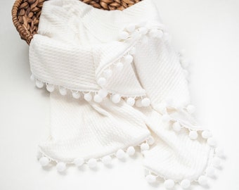 Babydeken.  Gebreide babydeken met pompons, witte babydeken, inbakerdeken, zachte babydeken