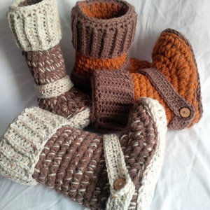 May include: Three pairs of crocheted boot cuffs in brown, white, and orange. The cuffs have a button detail and are made with a textured yarn.