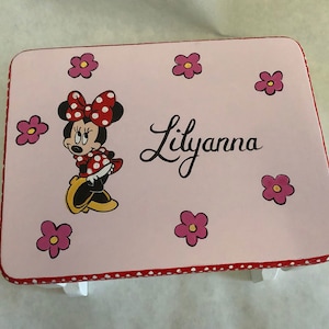 May include: A pink wooden step stool with a red and white polka dot trim. The top of the stool is painted with a cartoon image of Minnie Mouse, pink flowers, and the name "Lilyanna".