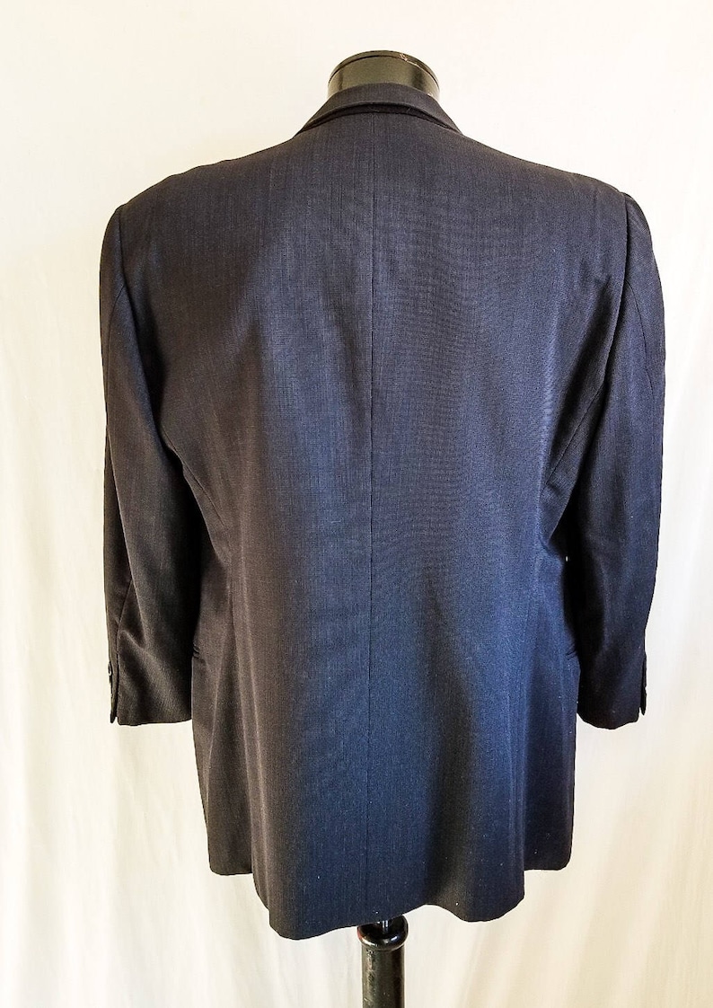 May include: A dark gray blazer with a single back vent. The blazer has a classic, tailored fit.