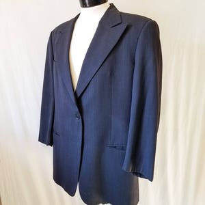 May include: A dark blue blazer with a single button closure and a pocket on the left side.
