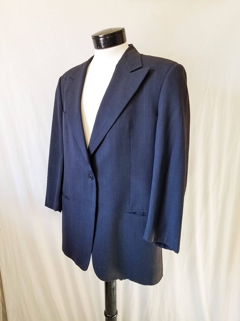 May include: A dark blue blazer with a single button closure and a pocket on the left side.