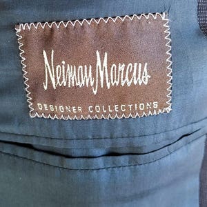 May include: A brown label with white stitching and the text "Neiman Marcus Designer Collections" on a dark blue fabric background.