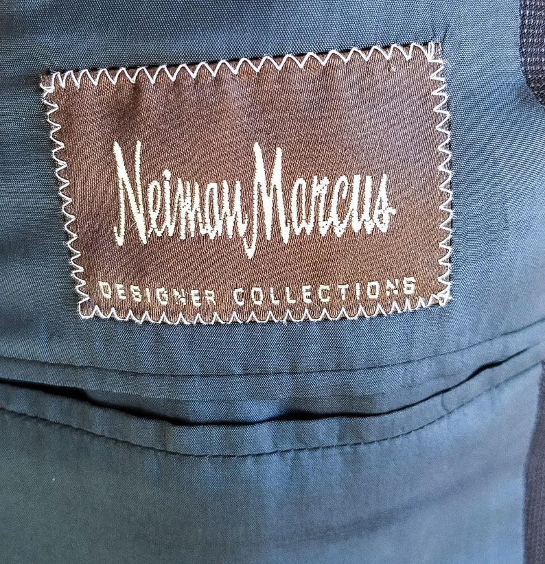 May include: A brown label with white stitching and the text "Neiman Marcus Designer Collections" on a dark blue fabric background.