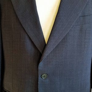 May include: A dark gray blazer with a single button closure and a textured fabric.