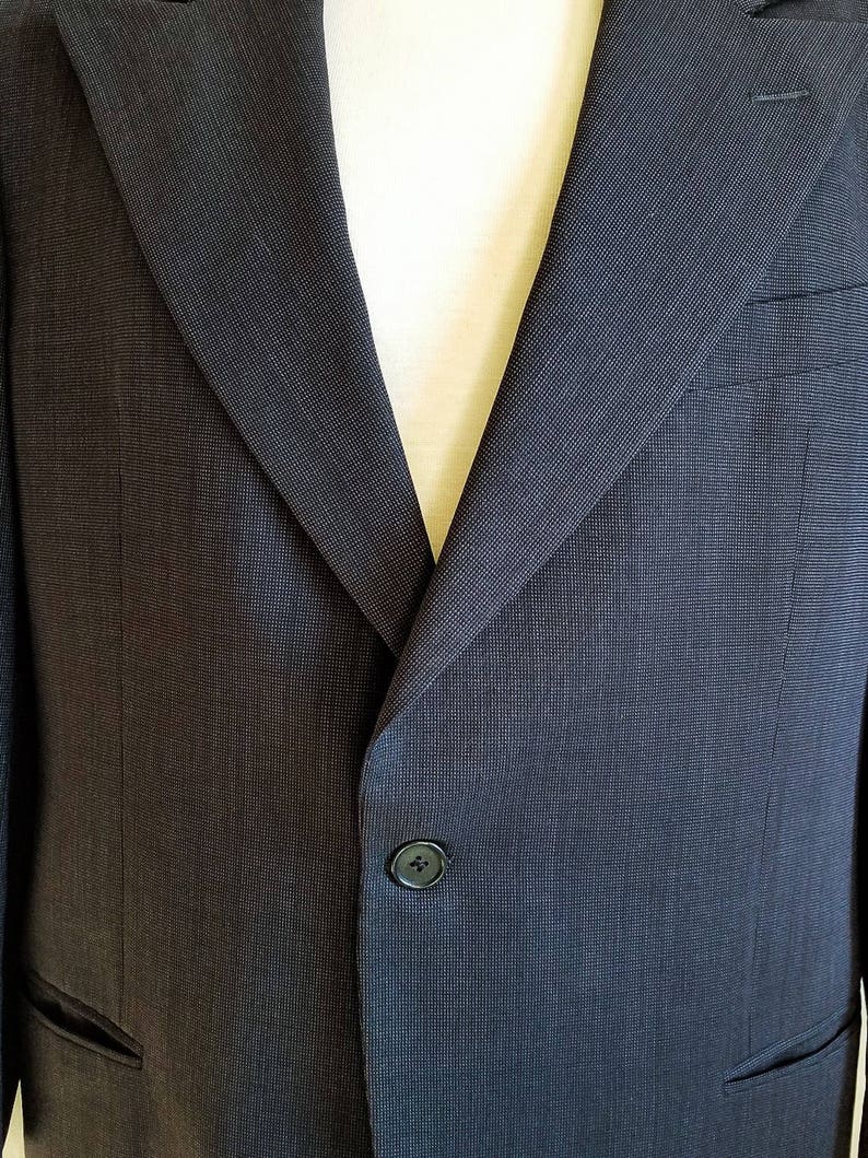 May include: A dark gray blazer with a single button closure and a textured fabric.