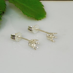 Puede incluir: Dos engastes de pendientes de plata con garras para sujetar una piedra preciosa. Los engastes están unidos a postes con cierres de mariposa.