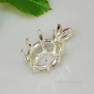 Puede incluir: Engaste de colgante de plata con una bisel redonda y un asa. El engaste tiene un engaste de garras alrededor del bisel.