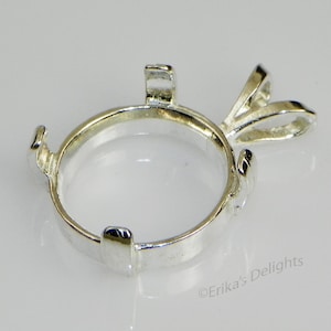 May include: Silver pendant setting with a round bezel for a stone or cabochon. The setting has a bail for attaching to a chain or cord.