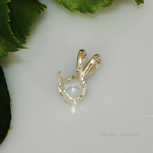 May include: Silver pendant with a round bezel setting for a gemstone. The pendant has a bail for attaching to a chain.