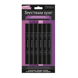 May include: A set of six Spectrum Noir alcohol markers in shades of purple and violet. The markers are double-ended, blendable, and refillable. The packaging features the brand name "Spectrum Noir" and the text "Professional Alcohol Markers".