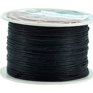 Puede incluir: Una bobina de cordón de algodón encerado negro. La bobina está etiquetada como "Natural Crafts" y tiene una advertencia de que no es para niños menores de 7 años.