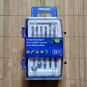 Peut inclure: Un kit de sculpture et de gravure Dremel bleu et blanc avec 11 pièces. Le kit comprend une variété d'outils de sculpture et de gravure, notamment une fraise ronde, une fraise conique et une fraise cylindrique. Le kit est emballé dans un étui en plastique transparent.