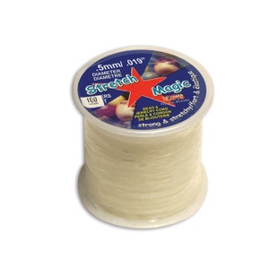 Może przedstawiać: Szpula przezroczystego, elastycznego sznurka do koralików i biżuterii. Szpula jest oznaczona tekstem "Stretch Magic" i "strong & stretchy/fort & élastique".