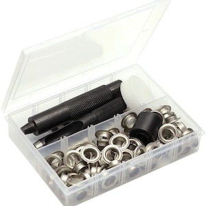 May include: A clear plastic storage box containing a set of metal eyelets and tools for installing them. The tools include a punch, a hammer, and a setting tool. The eyelets are silver and come in a variety of sizes.