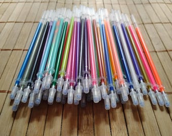 May include: A collection of colorful gel pens with clear plastic barrels and blue ink tips. The pens are arranged in a row on a wooden surface.