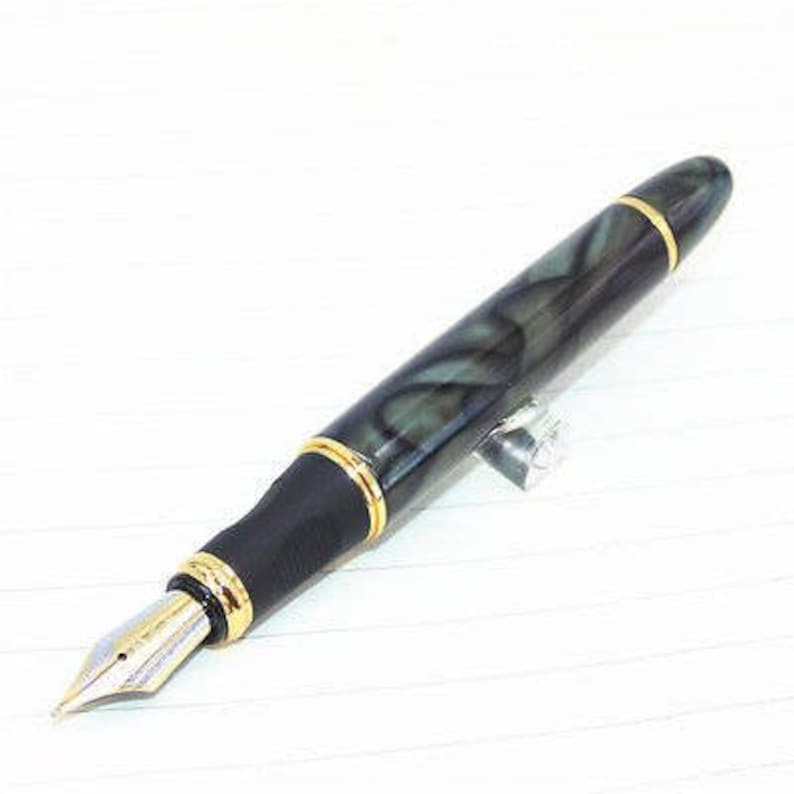 May include: A black and green fountain pen with gold accents and a fine nib. The pen has a marbled design.