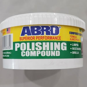 May include: A white and yellow container of ABRO Polishing Compound. The container has a white lid and a yellow label with the brand name and product information. The label also includes the American flag and the text "Superior Performance". The container holds 10 oz (295mL).