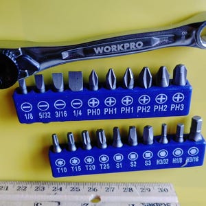 May include: A chrome WORKPRO ratchet spanner with an 8mm head, alongside two blue holders filled with screwdriver bits. The holders display sizes and types, including PH0, PH1, PH2, and T10, T15, T20. A ruler is at the bottom.