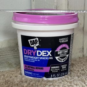 May include: A container of DAP DryDex heavyweight spackling. The white container has a pink lid and features the text "DRYDEX" and "HEAVYWEIGHT SPACKLING". It is 8 fl oz (236 ml). The product is for all drywall repairs.