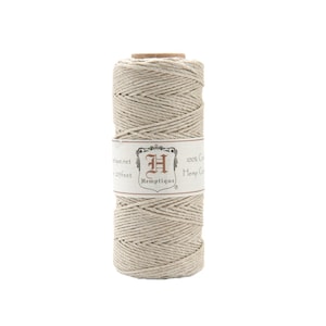 May include: A spool of natural-colored hemp twine. The label reads "Hemptique" and "100% Certified Hemp Cord". The twine is tightly wound around a cardboard core. The spool contains 205 feet of hemp cord.