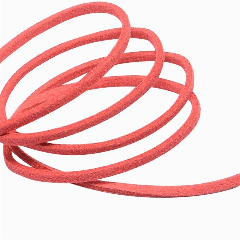 Puede incluir: Primer plano de un trozo de cord&oacute;n de ante de color coral, enrollado y en bucle sobre un fondo blanco. El cord&oacute;n tiene un aspecto suave y texturizado, con grano visible. La imagen destaca el color y la textura del cord&oacute;n, adecuado para manualidades o joyer&iacute;a.