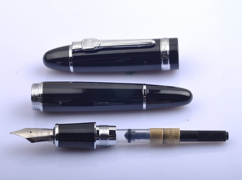 May include: A black fountain pen with a silver trim and a clear ink cartridge. The pen is in three pieces: the cap, the barrel, and the nib and ink cartridge assembly.