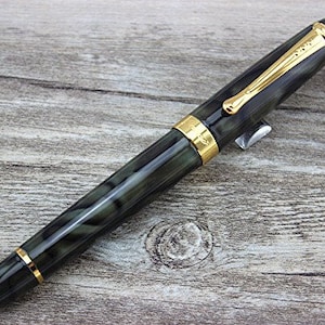 May include: A black and green fountain pen with gold accents and a black cap. The pen has a marbled design.
