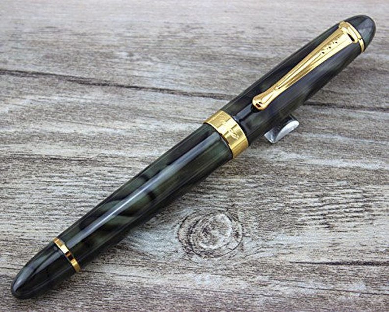 May include: A black and green fountain pen with gold accents and a black cap. The pen has a marbled design.