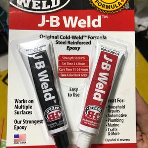 Könnte beinhalten: Zwei Tuben J-B Weld Epoxidkleber, eine mit der Aufschrift "Steel" und die andere mit der Aufschrift "Hardener". Das Produkt wird als "Original Cold-Weld™ Formula" und "Steel Reinforced Epoxy" beschrieben. Die Verpackung gibt auch an, dass das Epoxid eine Festigkeit von 5020 PSI, eine Abbindezeit von 4-6 Stunden, eine Aushärtungszeit von 15-24 Stunden und eine dunkelgraue Aushärtungsfarbe hat. Die Verpackung listet auch eine Vielzahl von Oberflächen auf, auf denen das Epoxid verwendet werden kann, darunter Metall, Holz, Kunststoff, Fliesen, PVC, Keramik, Glasfaser und Beton.