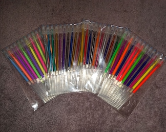 May include: A collection of colorful gel pens in individual plastic packaging. The pens are arranged in a fan shape, showcasing a variety of bright colors, including pink, purple, blue, green, yellow, orange, and red.